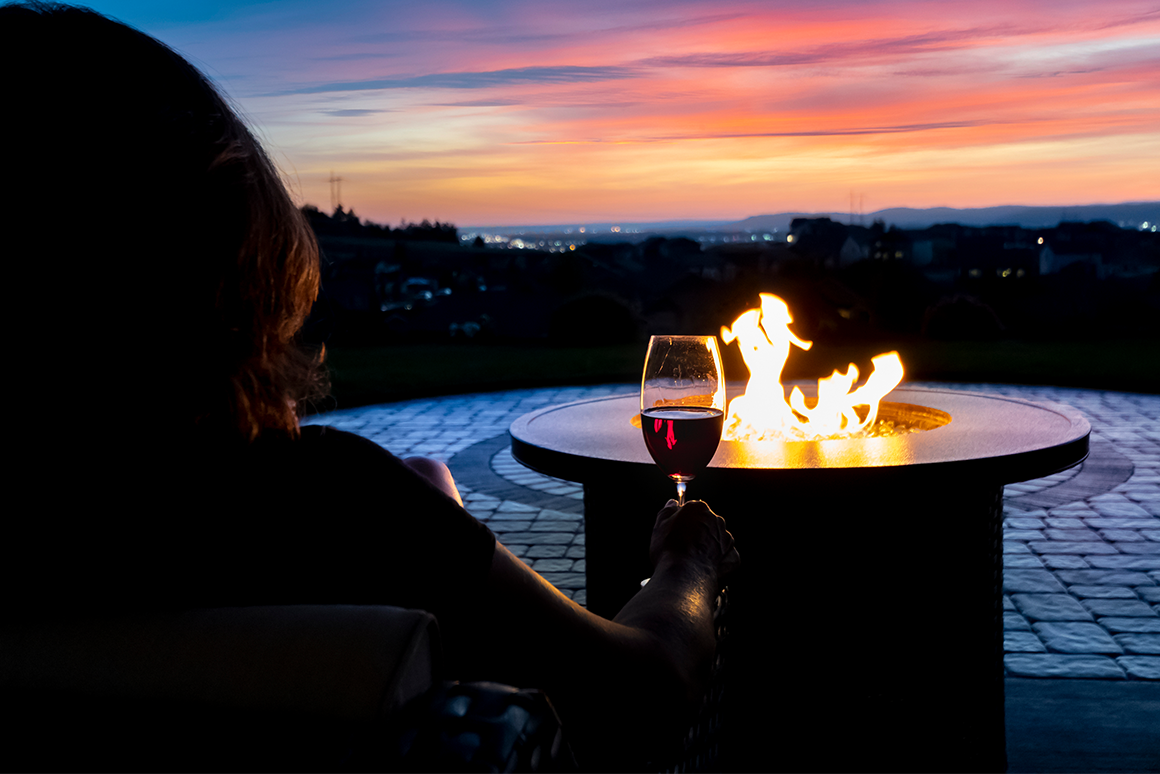 Woman drinking wine by an outdoor firepit