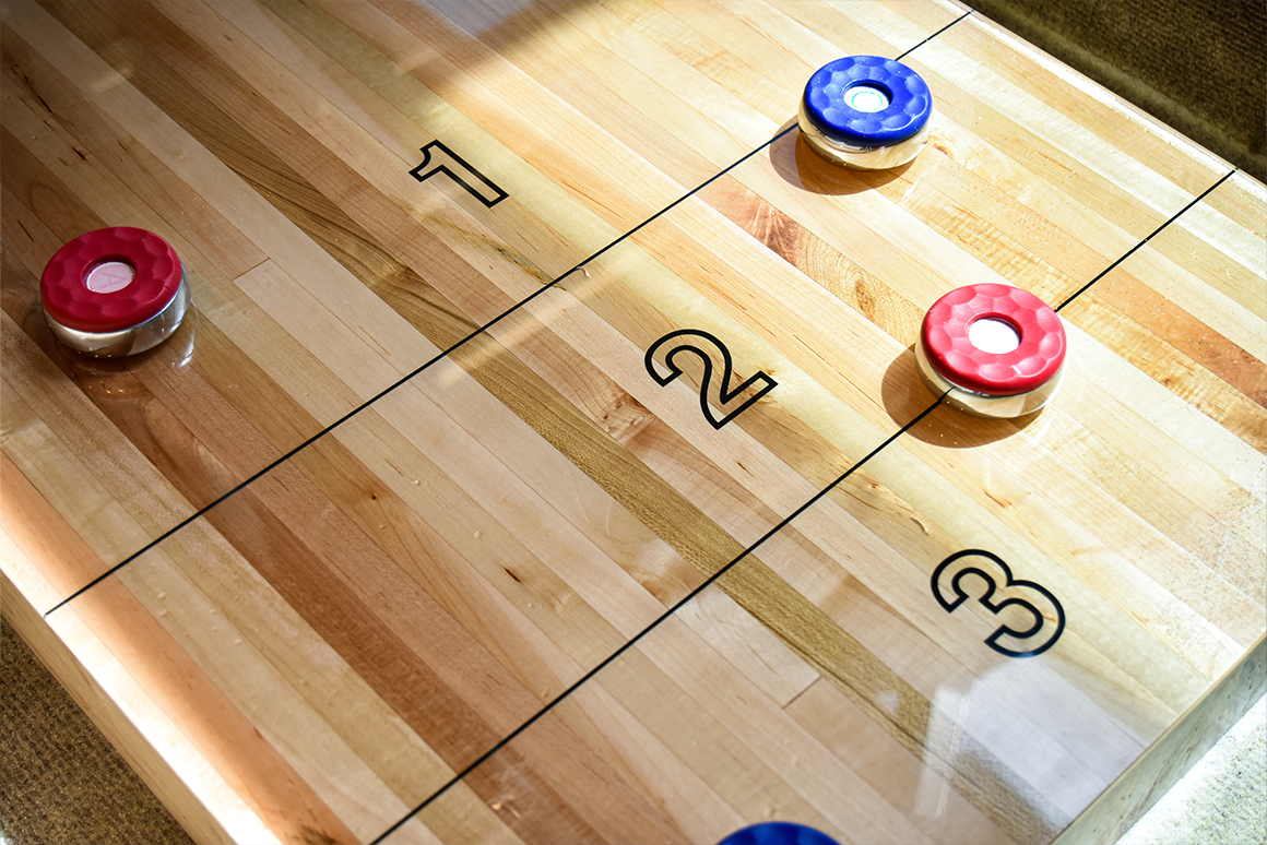 Guys drinking beer and playing shuffleboard in bar